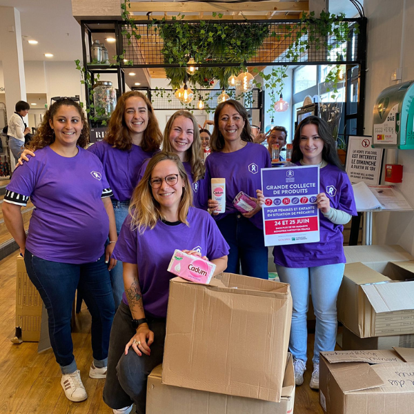 Bénévoles souriantes devant des cartons remplis de produits collectés